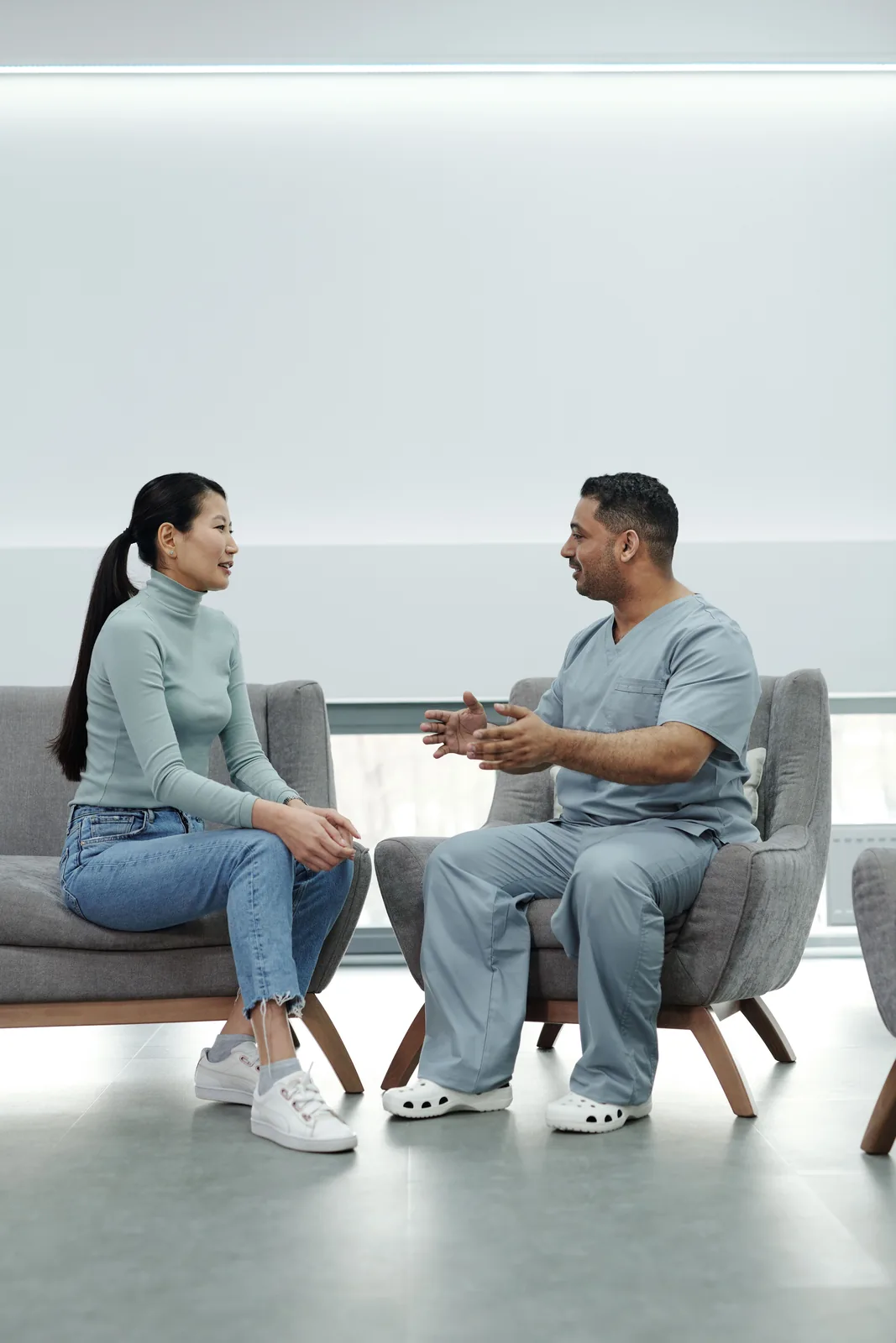 A clinician speaking with a patient in a bright modern clinic